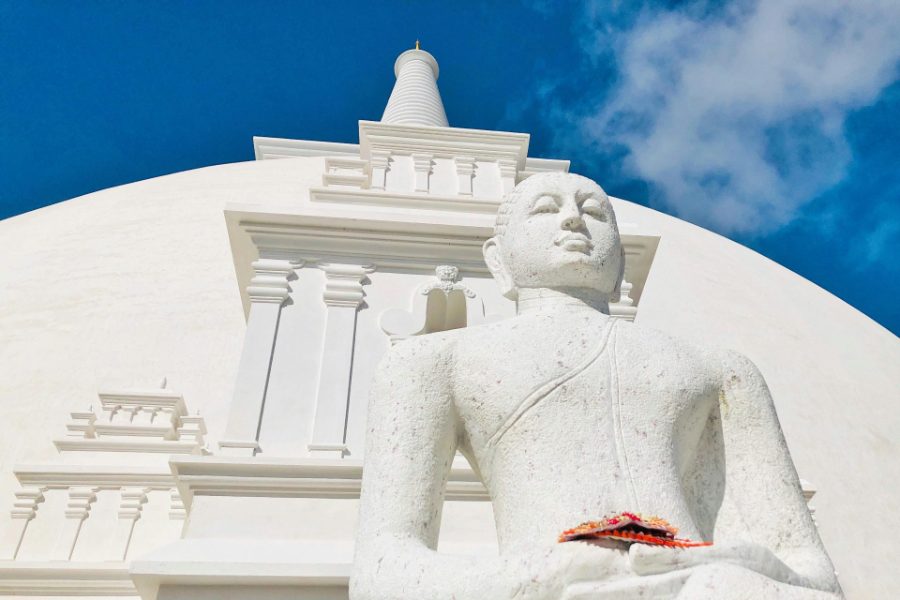 Bouddha de pierre blanche devant un grand stupa